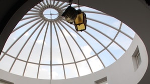 A room with a high, white, dome-shaped ceiling with skylights, a wooden railing, and a hanging lantern. - Hostel El Medina (Tunis)