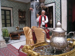 A traditional interior with ornate furniture, a large silver teapot, and a patterned wall. - Hostel El Medina (Tunis)