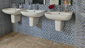 A bathroom with three sinks, a mirror, and patterned tiles. - Hostel El Medina (Tunis)