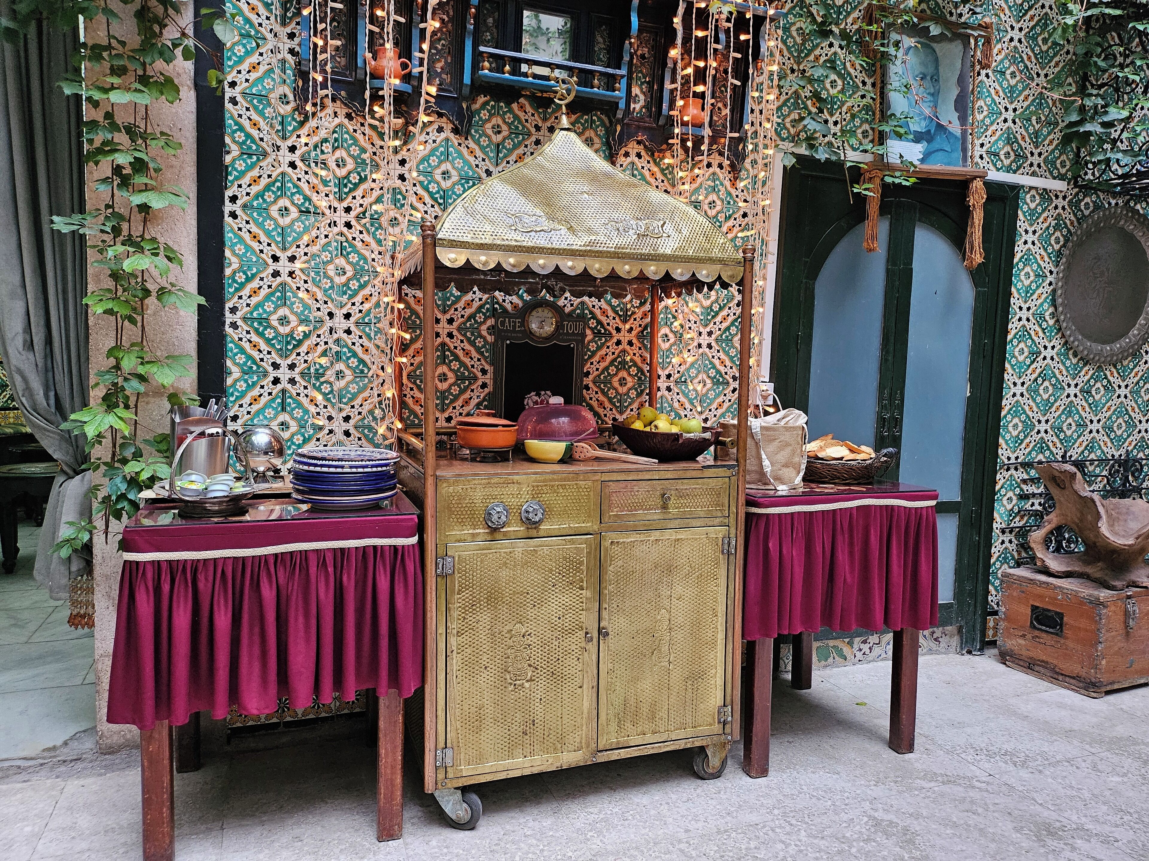 A traditional market stall with a canopy, a vintage cart, and a table with various items.
