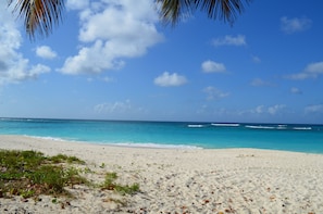 A sandy beach with clear turquoise water and a clear sky. - Villas at Indigo Reef (West End Village)