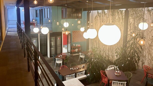 A modern interior with hanging spherical lights, a staircase, and a view of the outdoors. - Hotel MH (Chignahuapan)