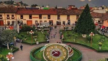 Una plaza con un reloj central, rodeada de edificios y vegetación.