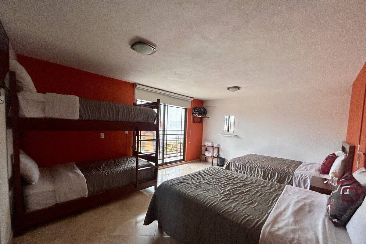 Una habitación de hotel con literas, un ventanal grande y un balcón.
