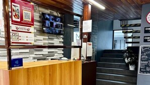 A hotel reception area with a wooden reception desk, a digital screen, and a sign with a QR code. - Hotel MH (Chignahuapan)