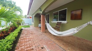 A brick pathway leading to a building with a hammock and a chair outside. - Jaco Villa 42 (León XIII)