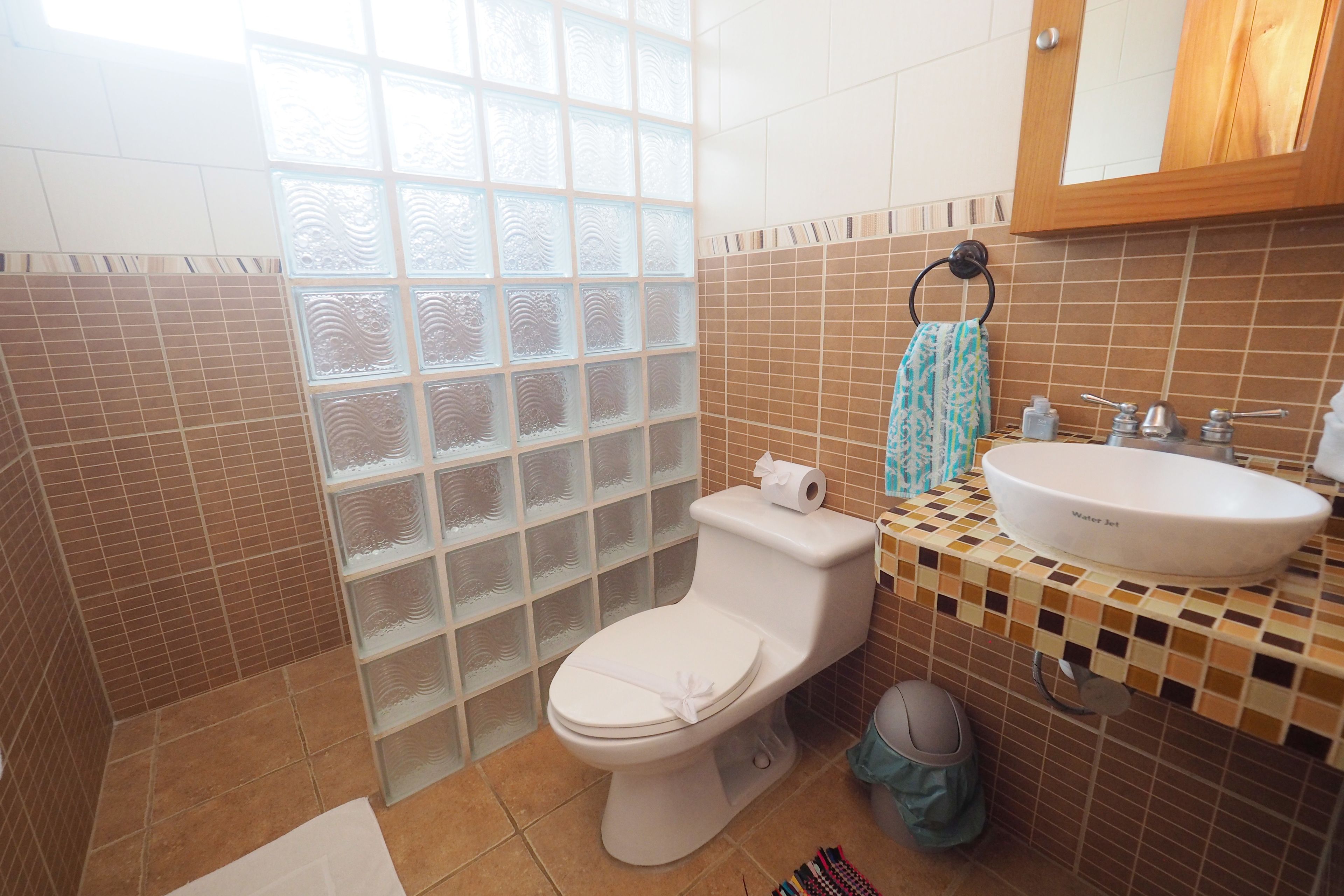 Un baño con inodoro, lavamanos y ventana con paneles de vidrio esmerilado.