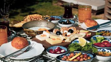 Una mesa servida con diversos alimentos y bebidas, como frutas, quesos y pan, indicando una preparación para comer al aire libre.