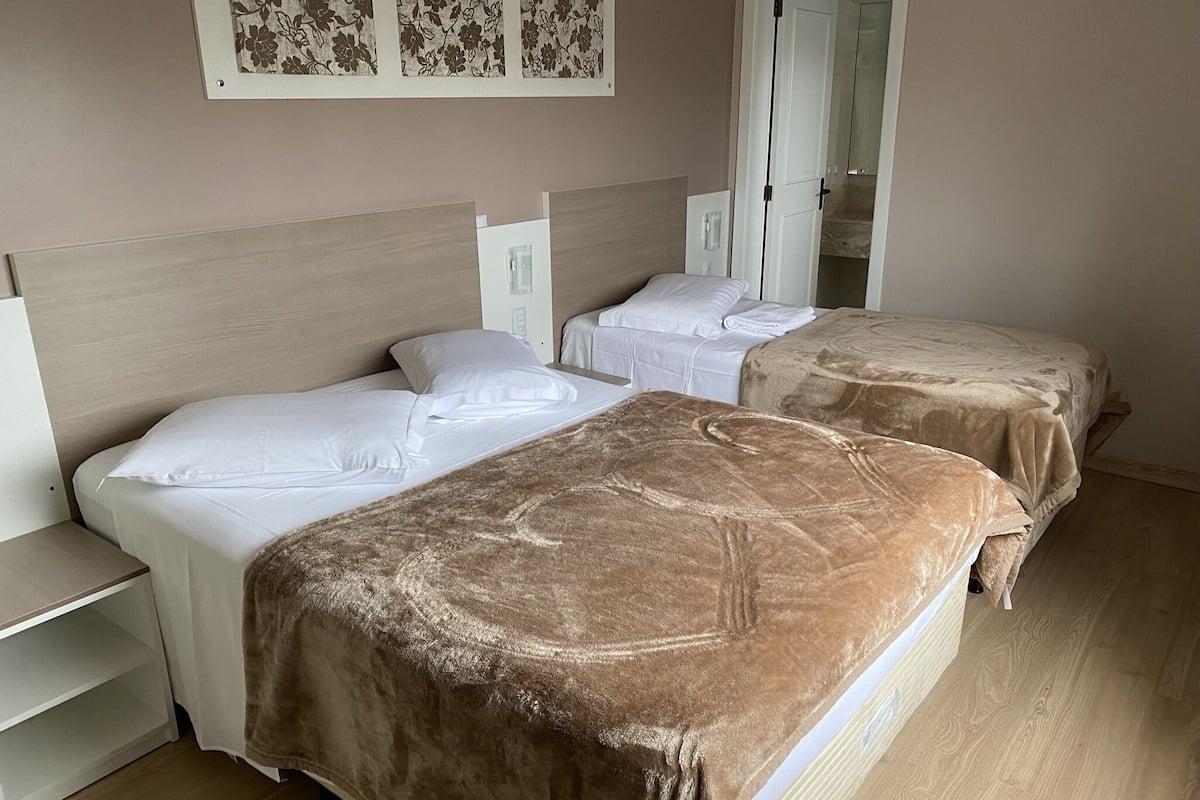 Una habitación de hotel con dos camas, una mesita de noche, un armario y un espejo.