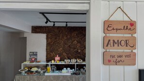 En frukostbuffé med ett varierat utbud av mat och en träskylt med texten ”Sprid kärlek vart du än går”.
