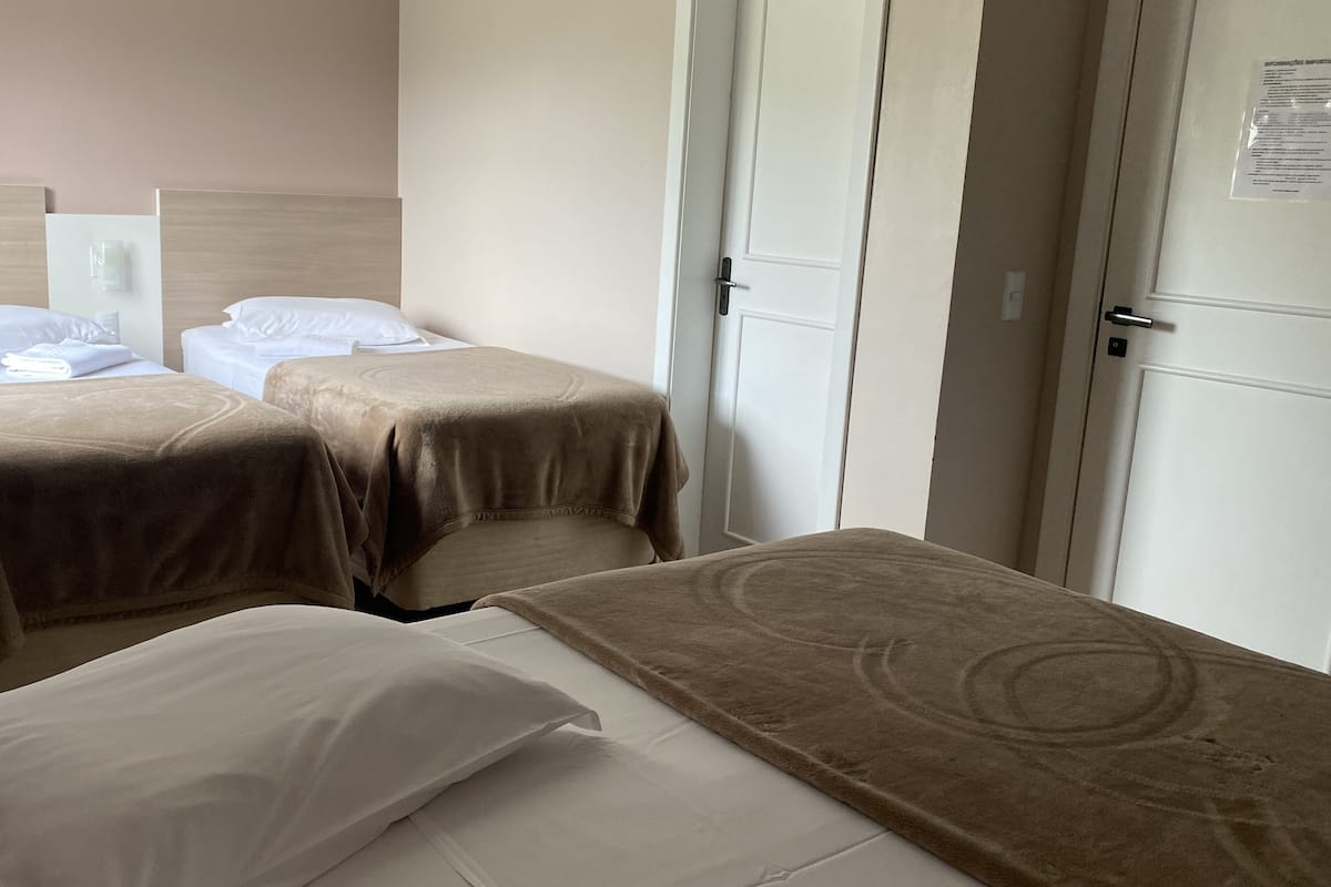 Una habitación de hotel con dos camas individuales, una mesita y una puerta.