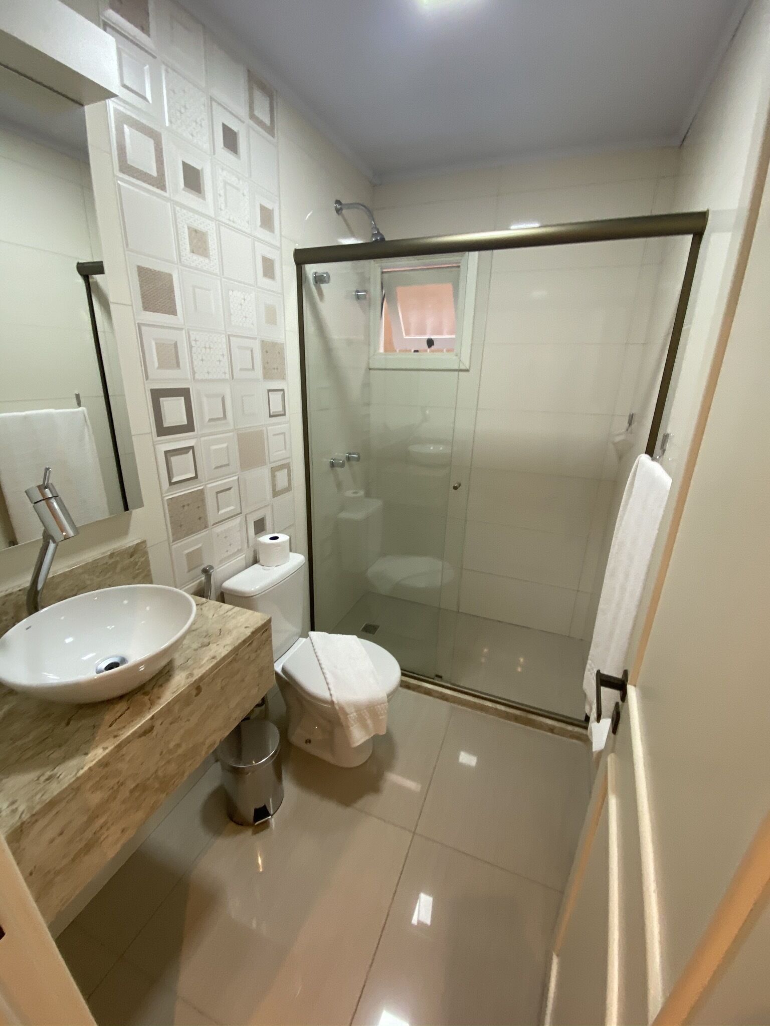 Un baño moderno con ducha de vidrio, lavamanos con encimera de mármol y retrete.