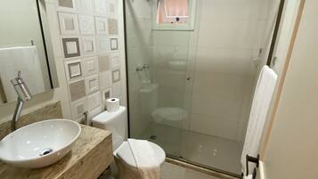 Un baño moderno con ducha de vidrio, lavamanos con encimera de mármol y retrete.