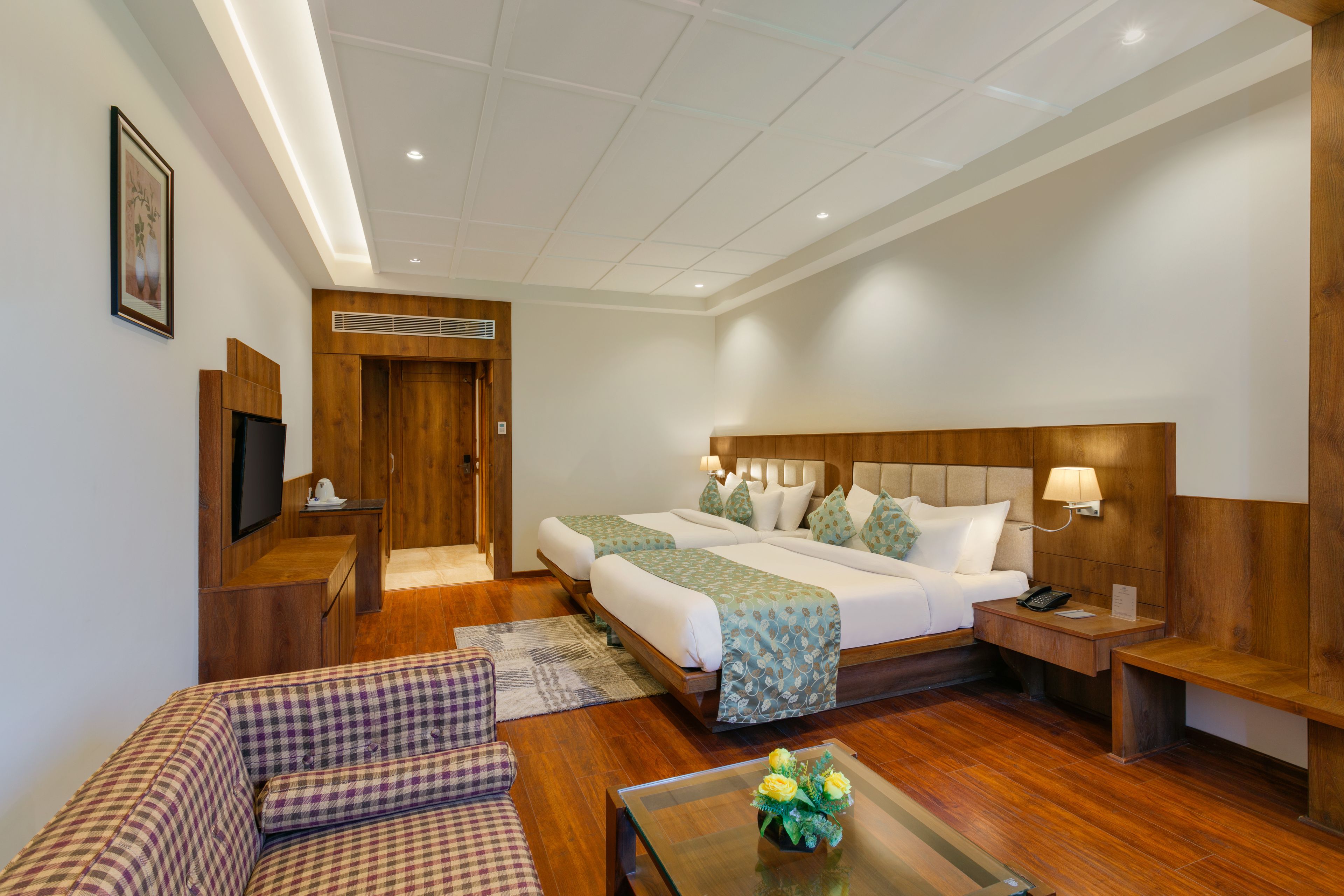 A hotel room with a large bed, a sofa, a coffee table, and a television.