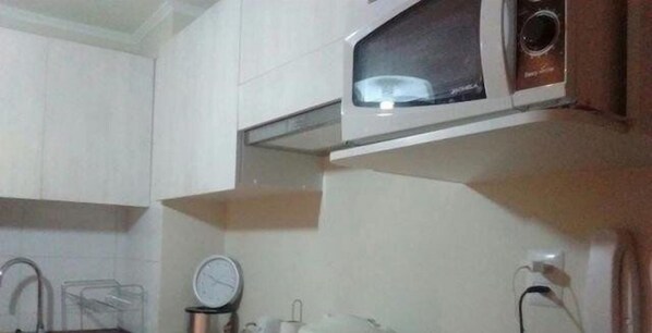 Une cuisine équipée d’un four à micro-ondes, d’une horloge et d’un évier.