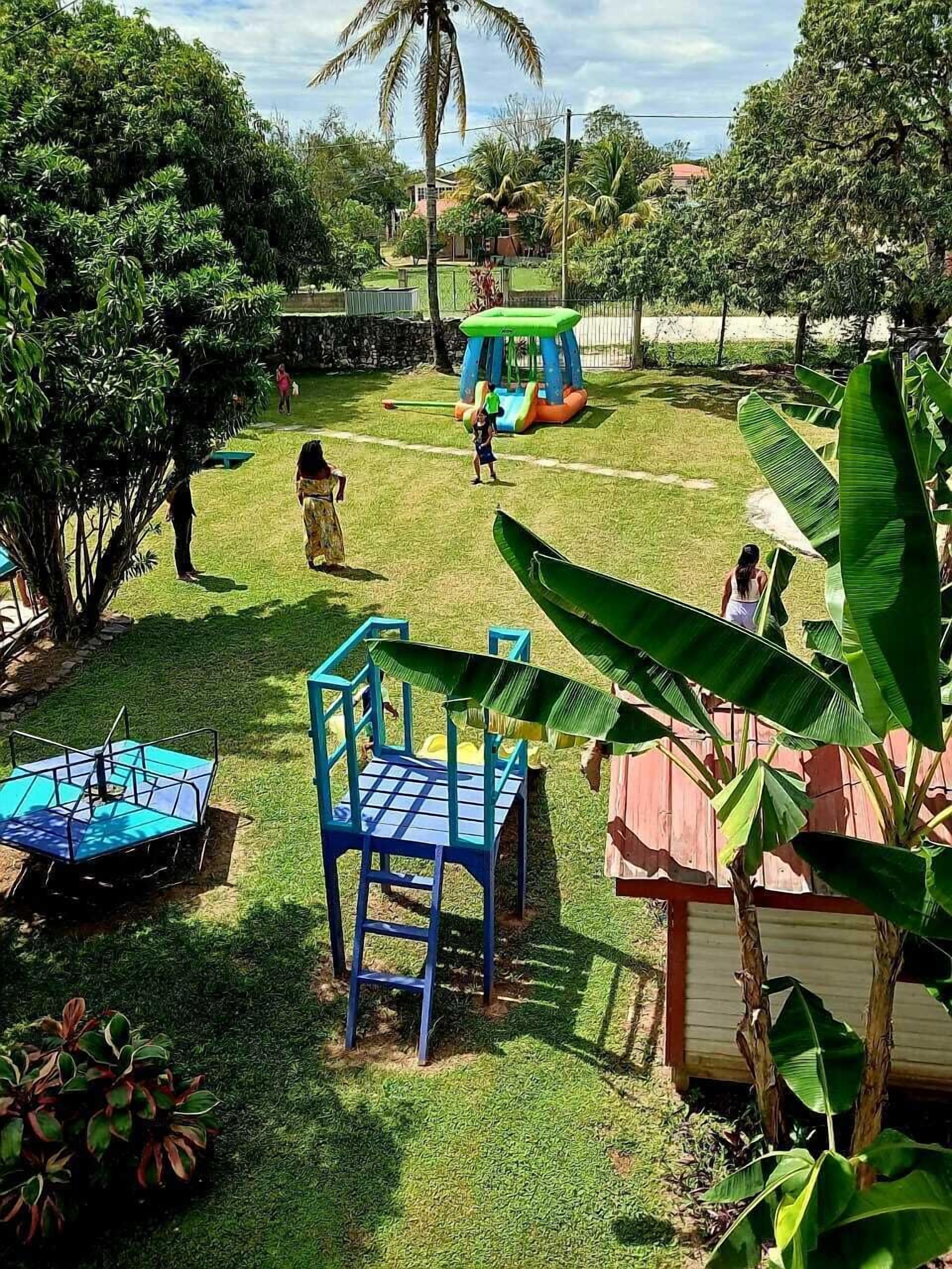 Un espacio al aire libre con césped, una estructura de juegos, una silla azul y una pequeña mesa azul.