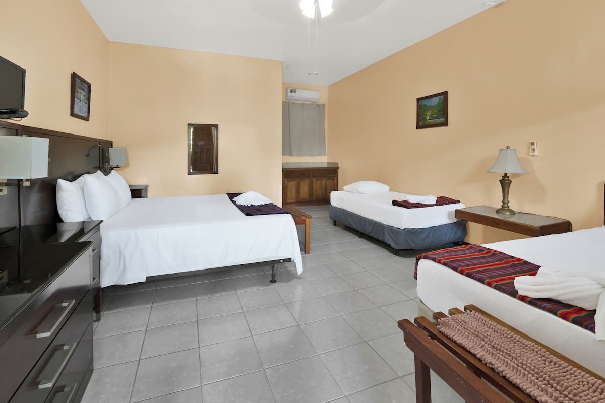 Habitación de hotel con dos camas, un escritorio, una silla, un televisor y un baño con cortina de ducha.