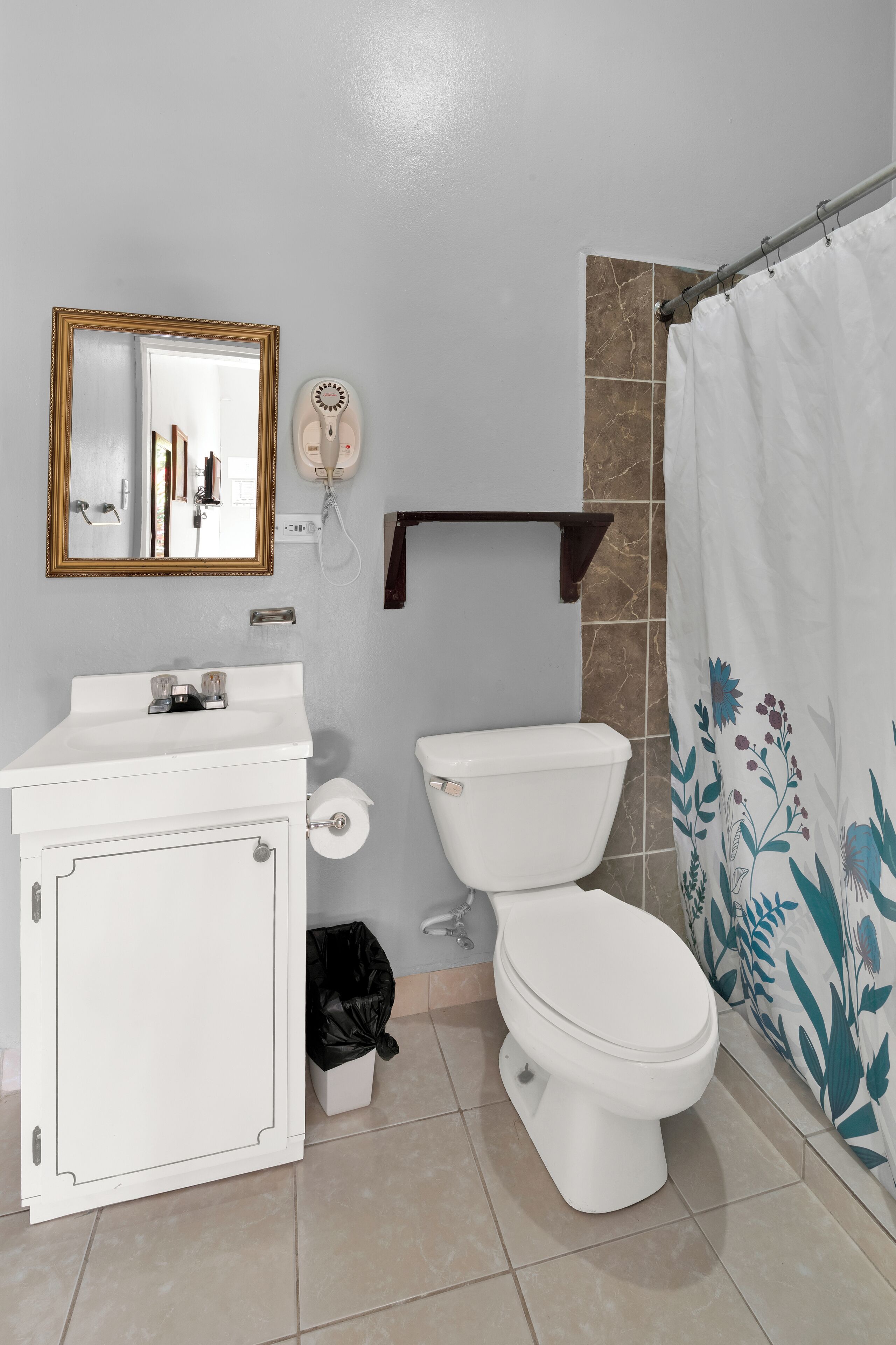 A bathroom with a white sink, a toilet, a mirror, and a shower curtain.