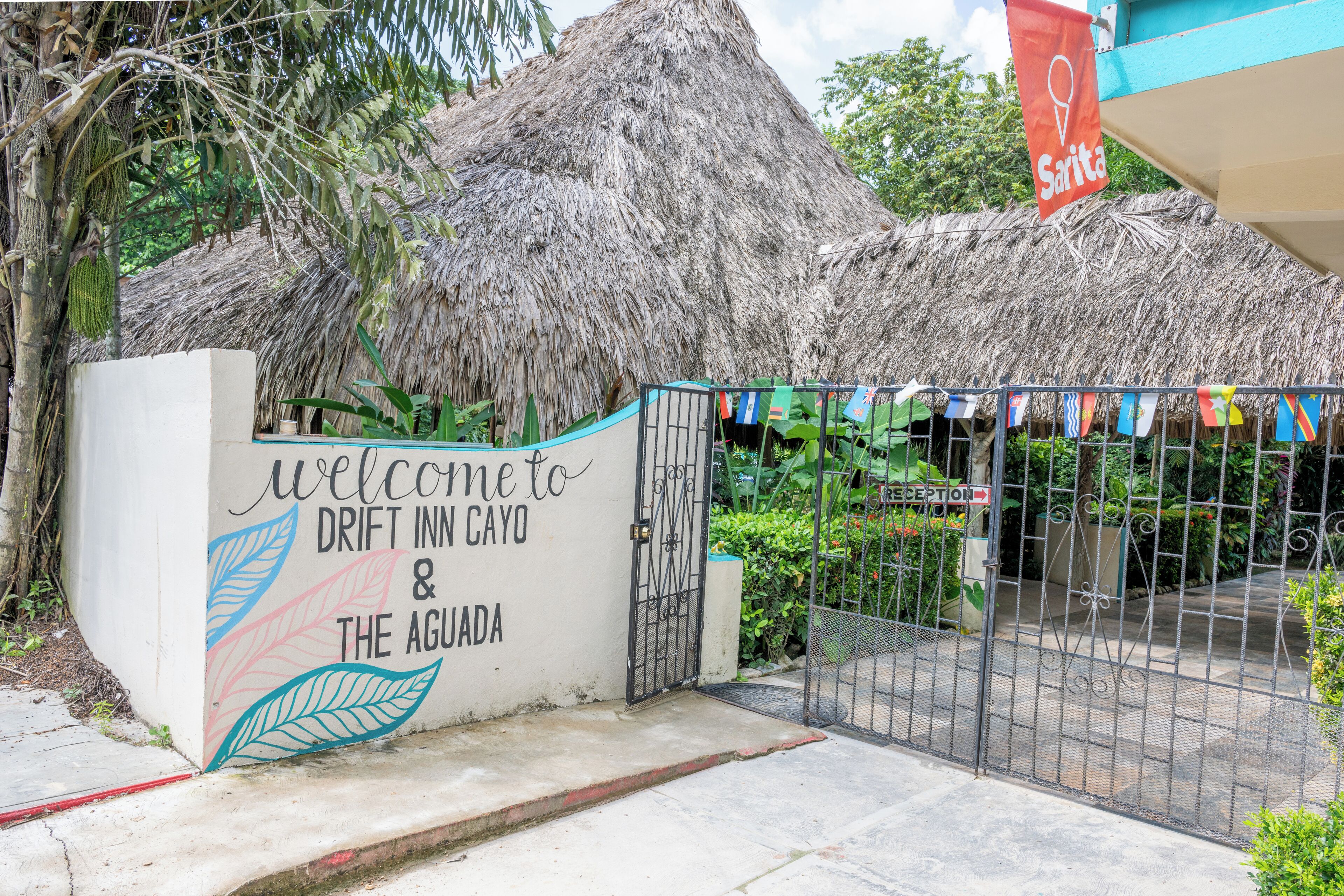 A welcoming sign for Drift Inn Cayu & The Aguada, featuring a thatched roof and lush greenery.