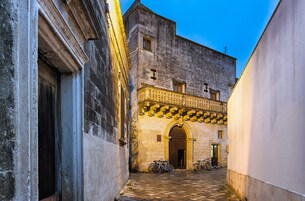 Un estrecho callejón con un edificio histórico que presenta una entrada ornamentada y un balcón.