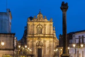 A historic building with ornate architecture, a prominent column, and street lamps. - Palazzo Muro Leccese Relais de Charme (Muro Leccese)