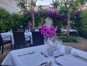 An outdoor dining area with tables set for a meal, surrounded by lush greenery and flowering plants. - Palazzo Muro Leccese Relais de Charme (Muro Leccese)