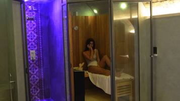 Een spa-ruimte met een glazen scheidingswand, een houten bank en een vloer met een patroon.