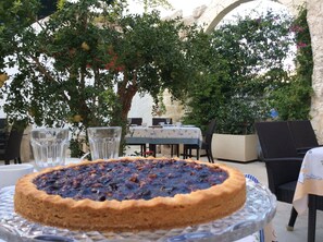 A pie on a glass plate, a table with chairs, and a stone archway in the background. - Palazzo Muro Leccese Relais de Charme (Muro Leccese)