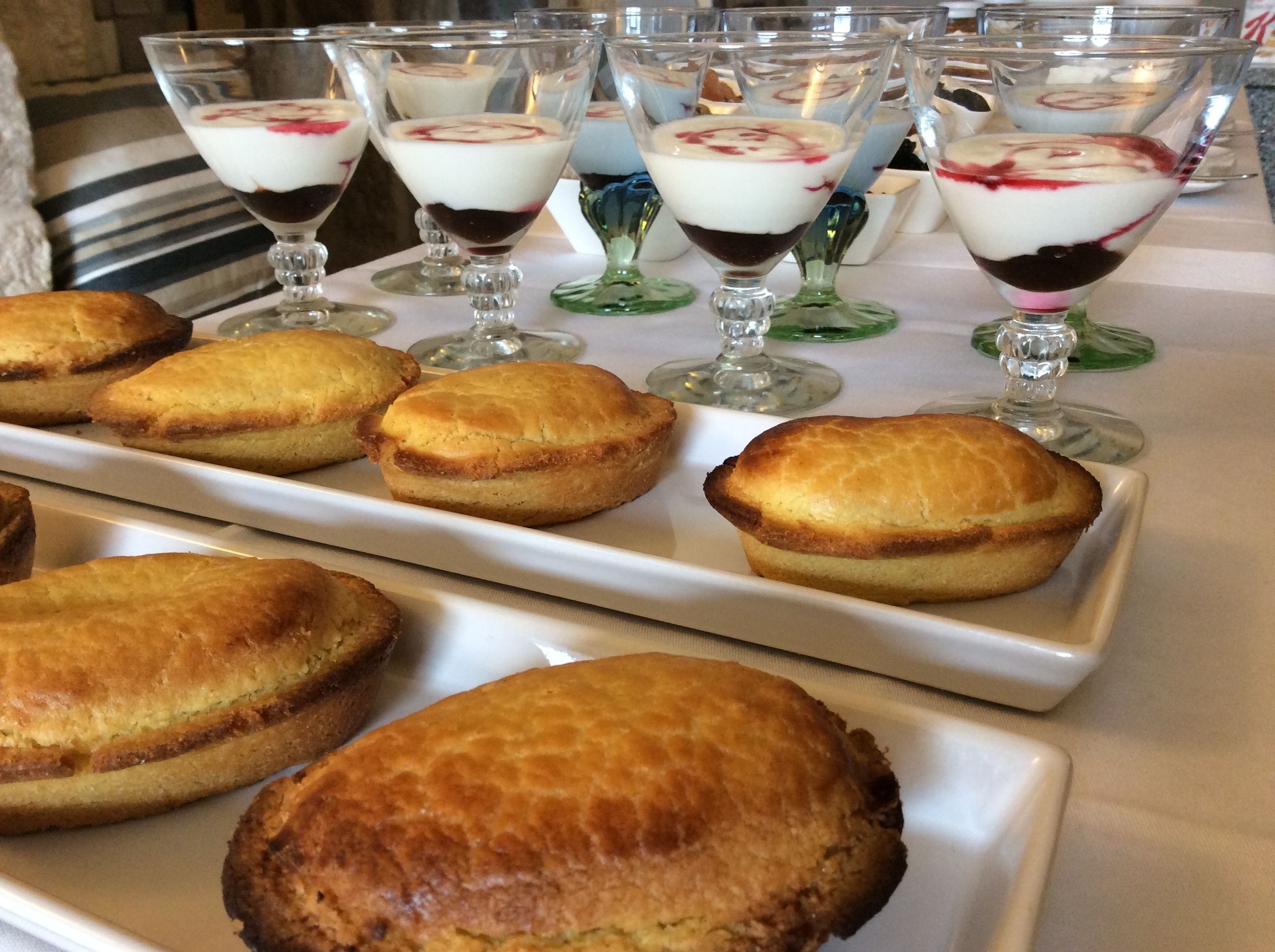 A table with desserts including layered parfaits and pastries.