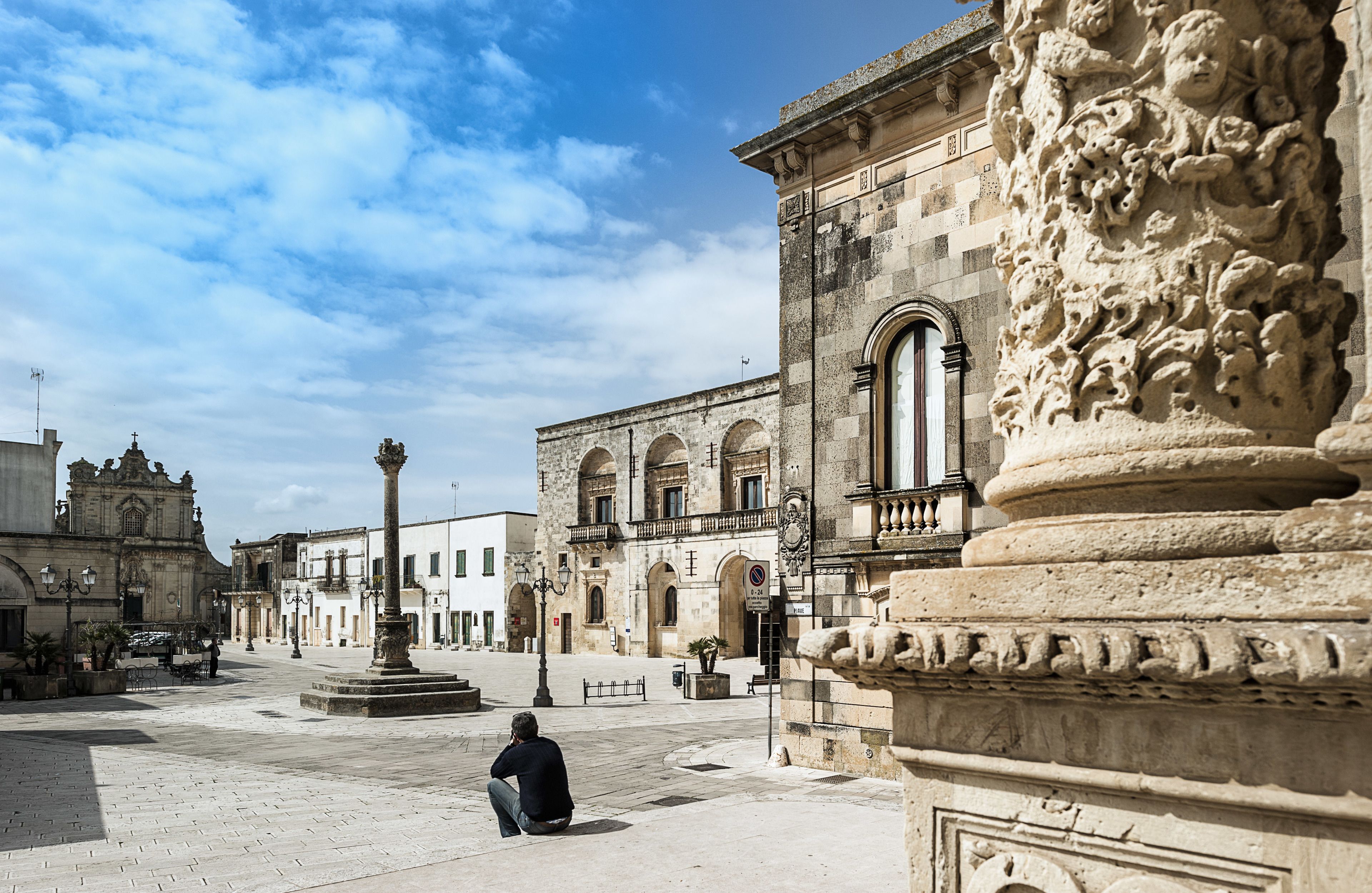 A historic plaza with a central fountain, ornate columns, and classical architecture.