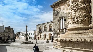 Una plaza histórica con una fuente central, columnas ornamentadas y arquitectura clásica.
