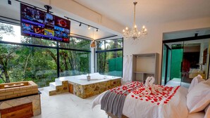A modern bedroom with a large bed, a stone bathtub, and a TV mounted on the wall. - Resort Magnífico (Camanducaia)