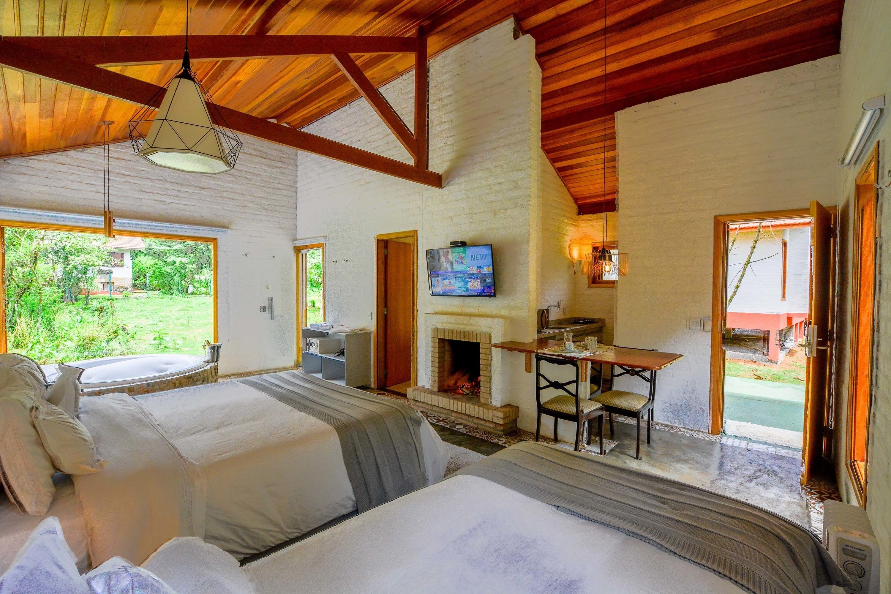 A room with two beds, a fireplace, a television, and a dining area.