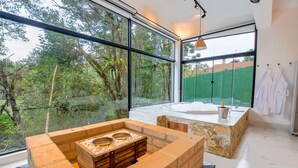 A modern bathroom with large windows, a stone sink, and a bathtub. - Resort Magnífico (Camanducaia)