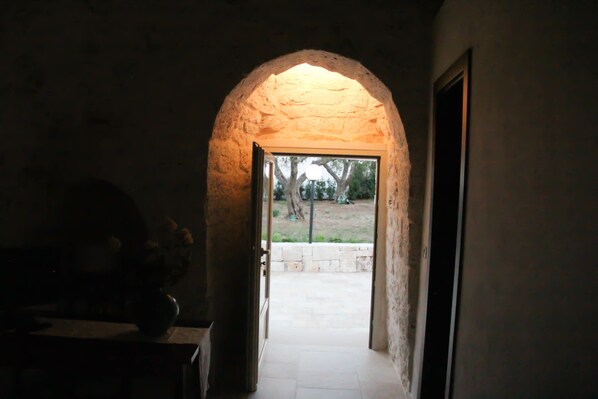 Un arco de entrada da a un espacio exterior con un muro de piedra y un árbol.