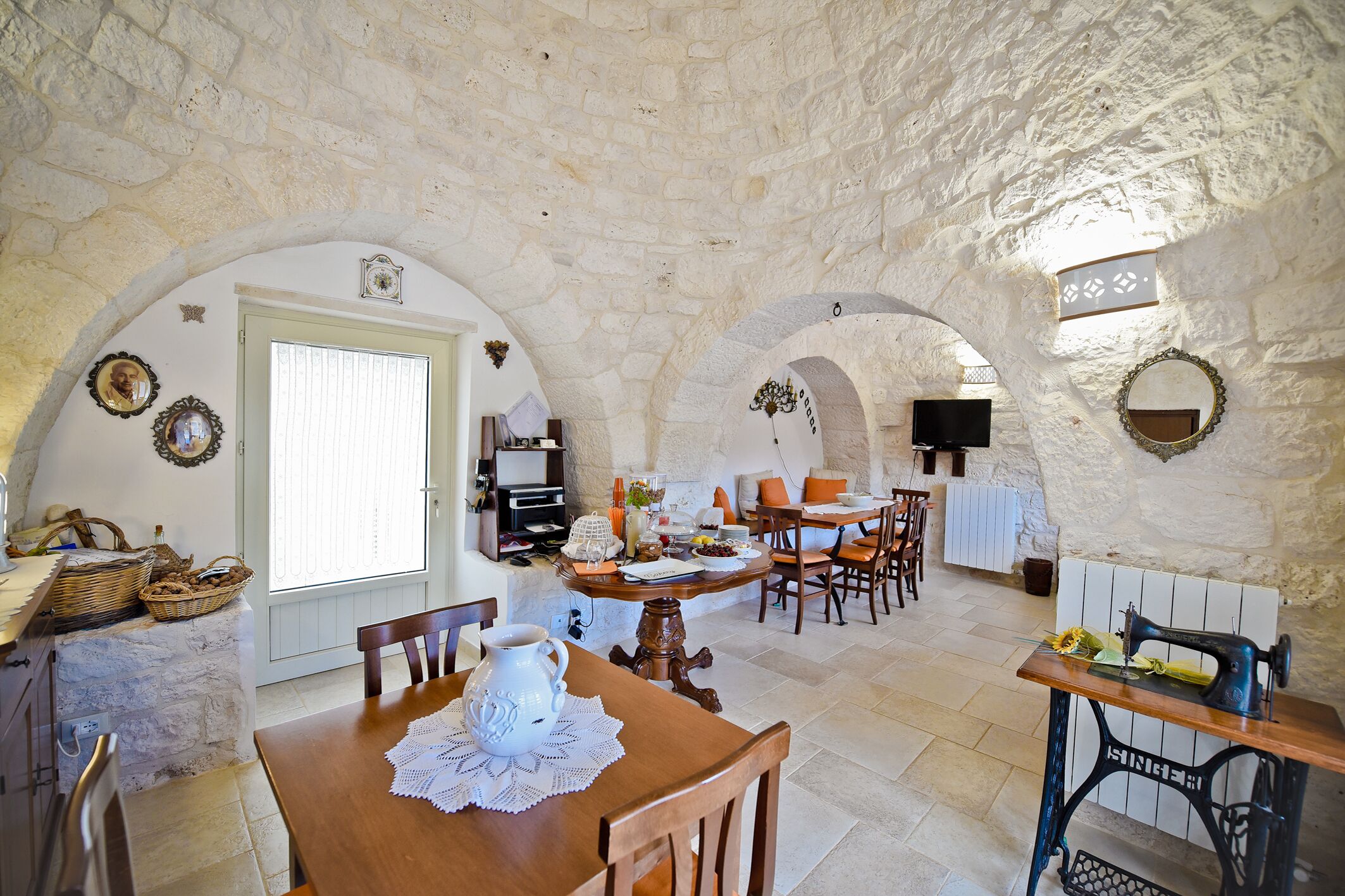 A rustic dining area with stone walls, wooden furniture, and a vintage sewing machine.