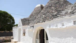 Un edificio de piedra con fachada blanca, una puerta y un ventanal pequeño.