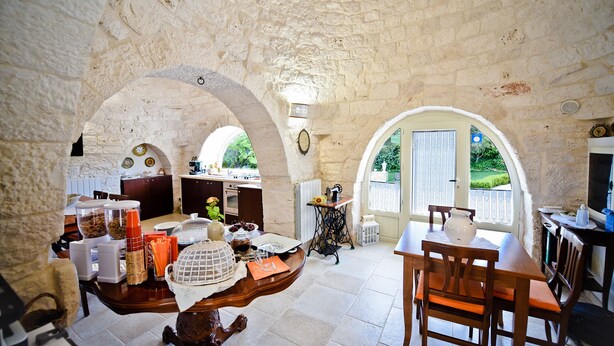 Cocina de piedra rústica con comedor, que incluye una mesa grande, sillas y vistas al exterior.