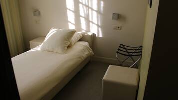 A neatly arranged bedroom with a bed, bedside tables, and a chair.