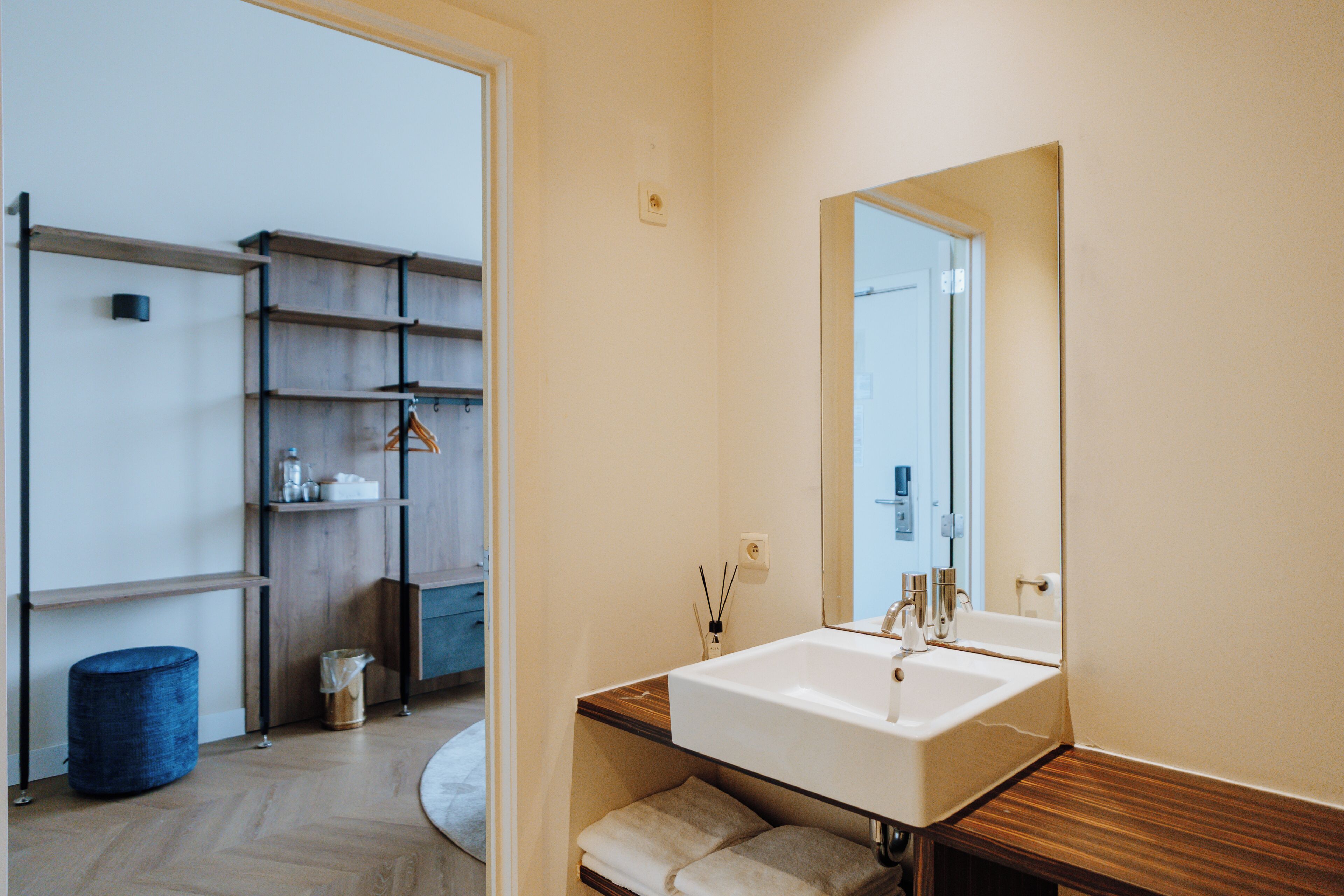Un baño moderno con un espejo grande, un lavamanos y estantes de madera.