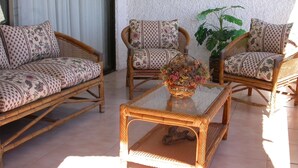 A room with wicker furniture, including two sofas and two armchairs, a glass coffee table, and a potted plant. - Puerto Velero Andrea Meza 2 (Coquimbo)