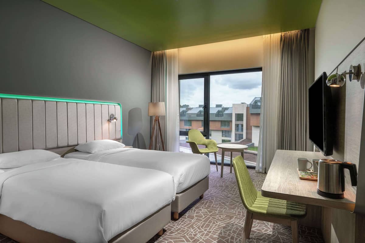 Een hotelkamer met twee bedden, een bureau met waterkoker, een stoel en een televisie.
