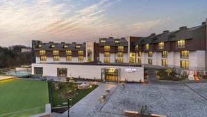 Ein modernes Hotel mit flachem Dach, mehreren Balkonen und einem gut beleuchteten Eingang.