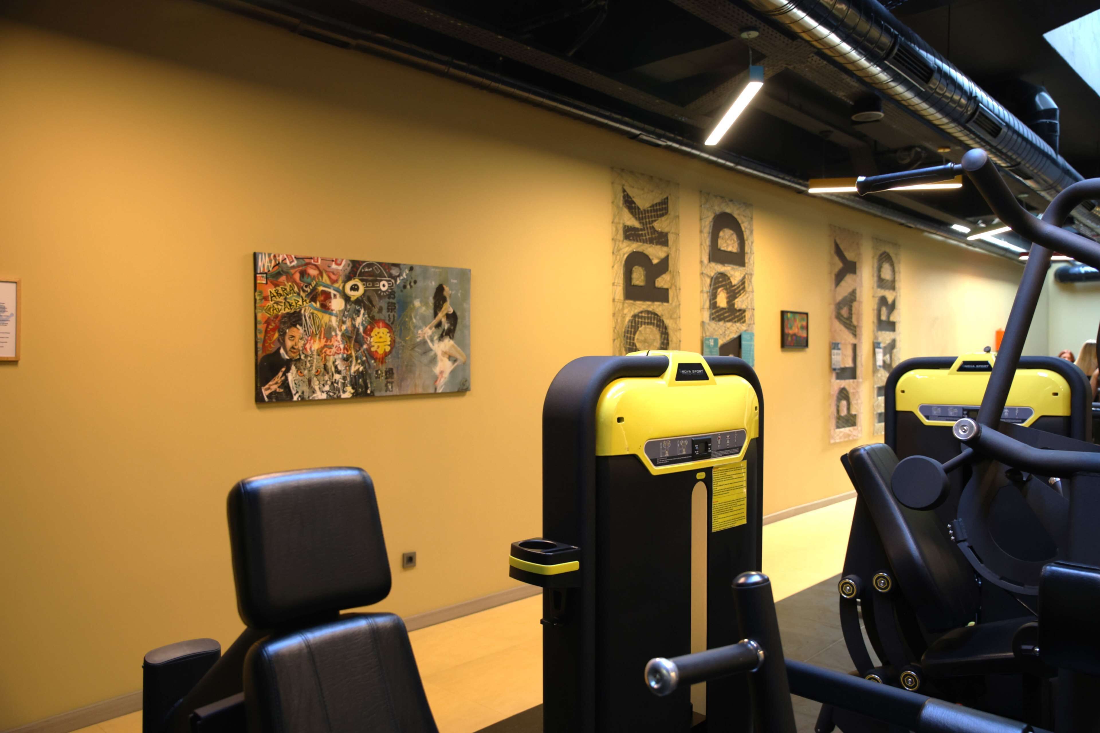 A gym with exercise equipment and a mural on the wall.