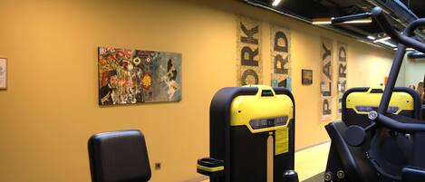 A gym with exercise equipment and a mural on the wall.