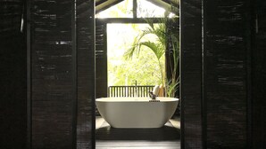 A large bathtub under a wooden structure with a view of greenery outside. - KAJU GREEN eco lodges (Unawatuna)