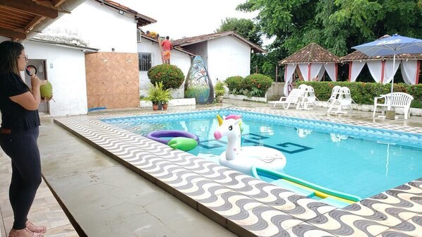 Piscina com flutuador de cisne, espreguiçadeiras e deck revestido de azulejos.