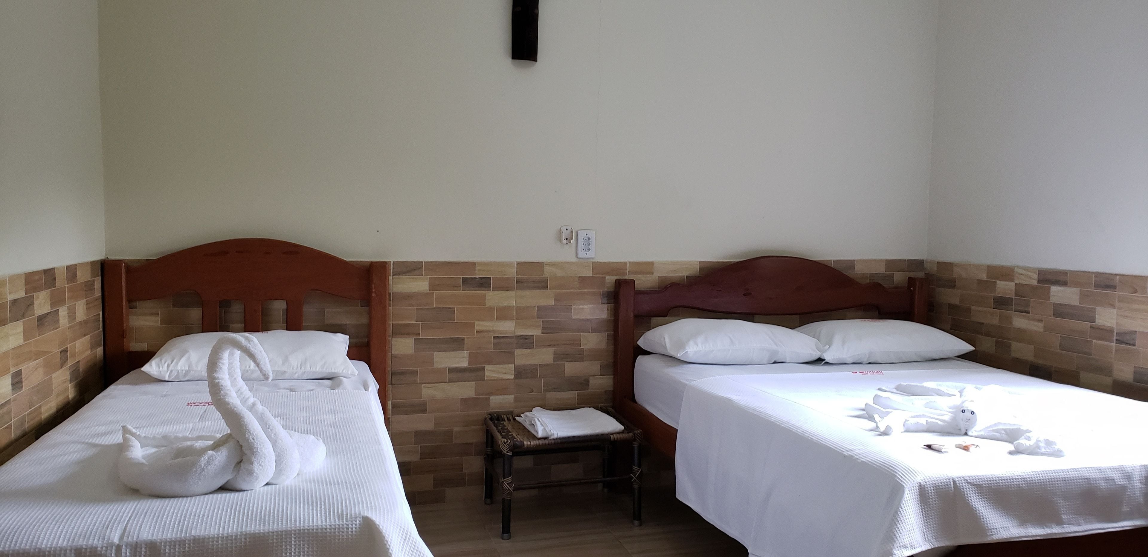 Two single beds with wooden headboards, white bedding, and a small bench between them.