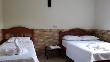 Two single beds with wooden headboards, white bedding, and a small bench between them.
