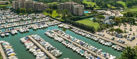Een jachthaven met tal van boten afgemeerd in rijen, omringd door weelderige begroeiing en gebouwen.